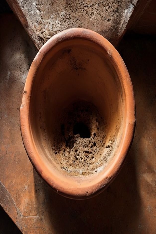 An overhead shot of a terracotta pot s base clearly showing a well-defined unpainted drainage hole with a small pile of