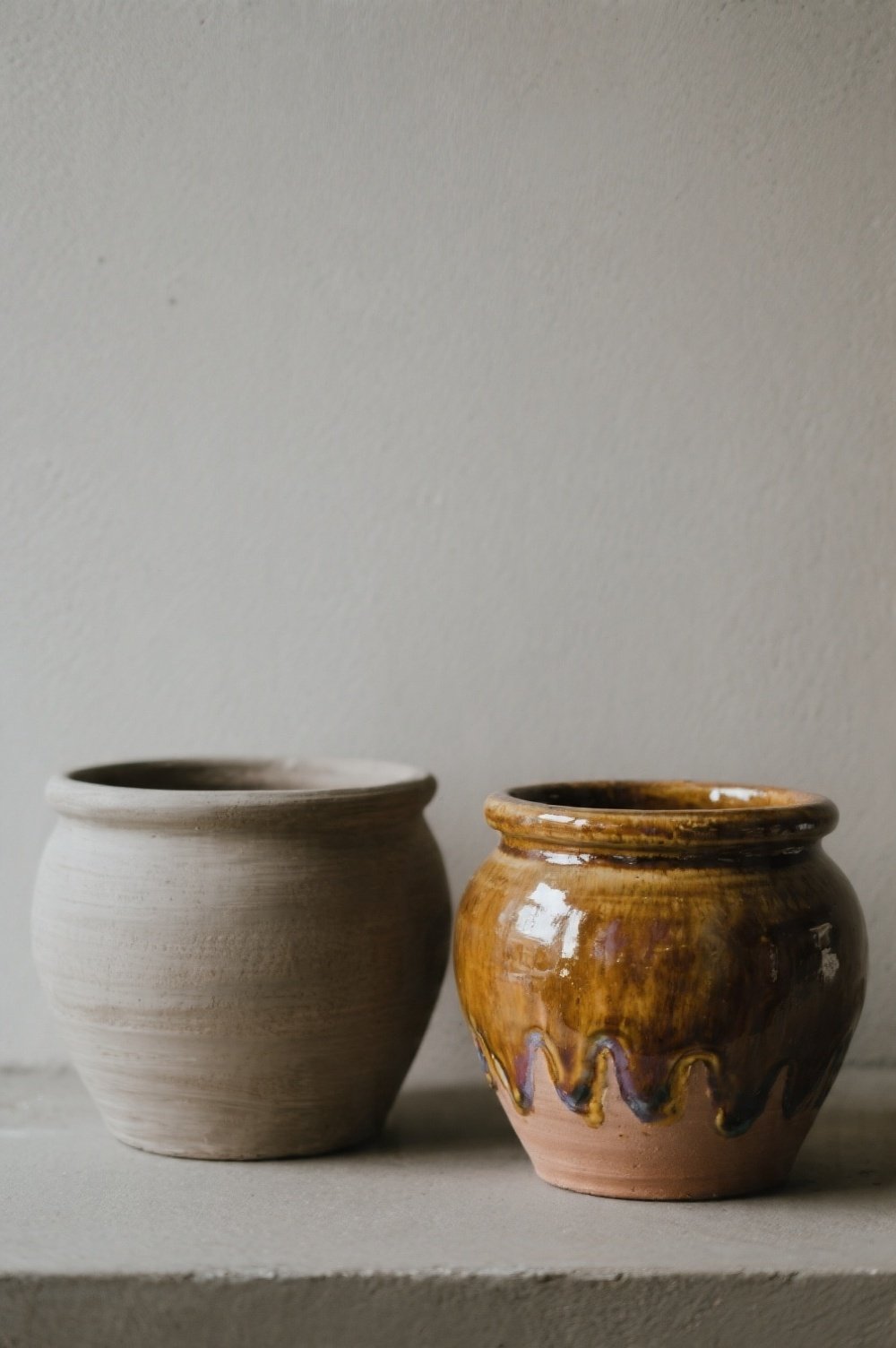 Two painted pots side-by-side one with a matte finish the other with a glossy glaze highlighting the depth and sheen Lus