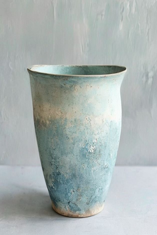 An aged-look painted flower pot with a subtle translucent blue-gray wash applied over a light base creating a weathered