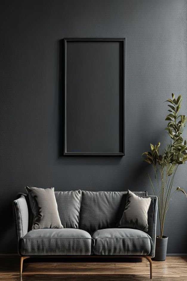 A close-up shot of a small solitary framed picture hanging noticeably too high above a large deep charcoal grey three-se