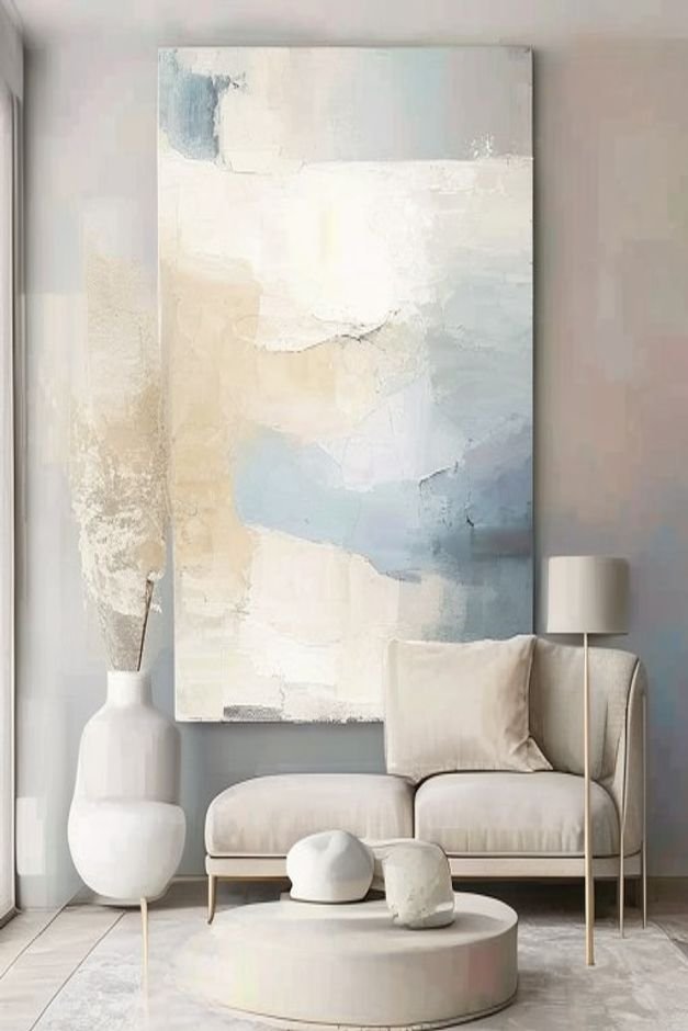 A large abstract painting in subtle calming tones of cream light gray and muted blue featuring broad expressive brushstr