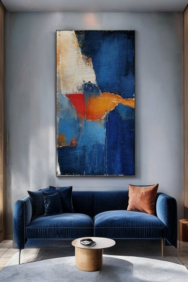 A minimalist living room featuring a deep blue velvet sofa Above it a single oversized striking abstract painting in war