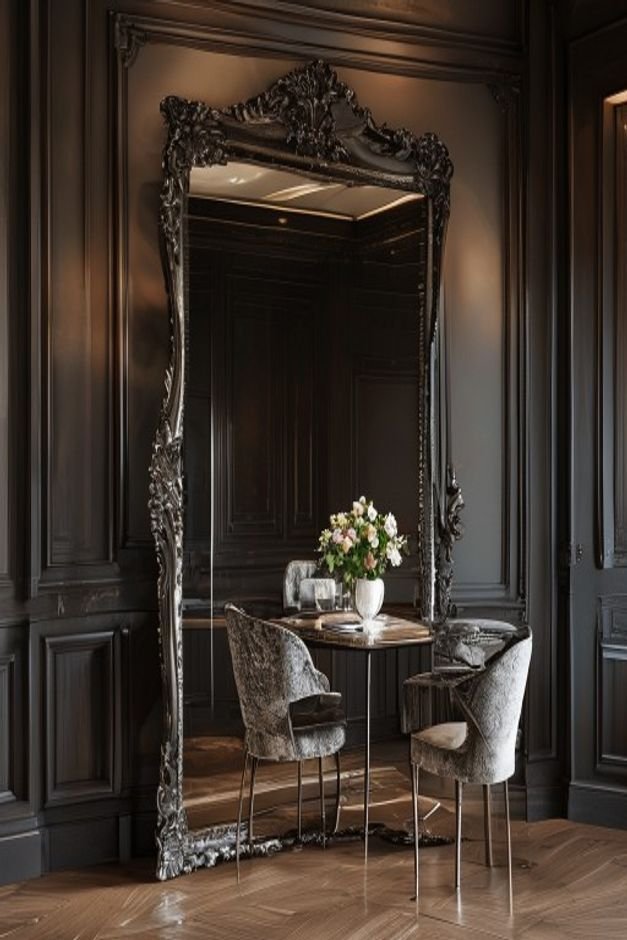 An elegant dining room featuring a grand oversized mirror with a dark wood frame leaning against a wall reflecting a cha