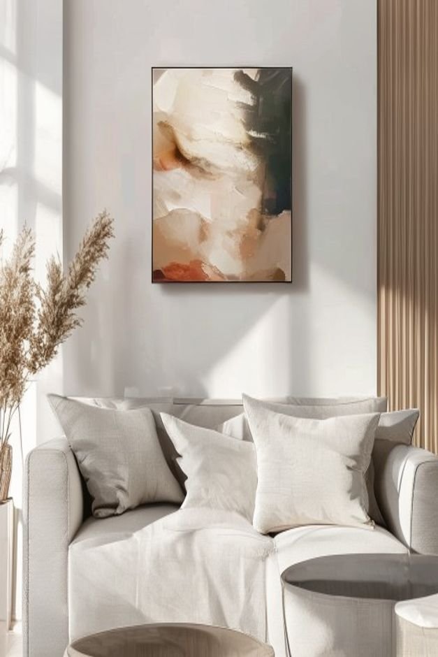 A close-up eye-level shot of a perfectly scaled piece of abstract art hanging above a modern minimalist sofa in a light-