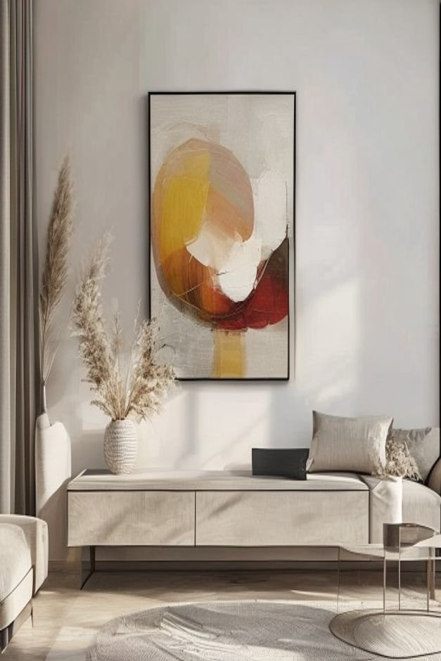 A modern living room with a large framed abstract painting casually leaning against the wall on a low console table behi
