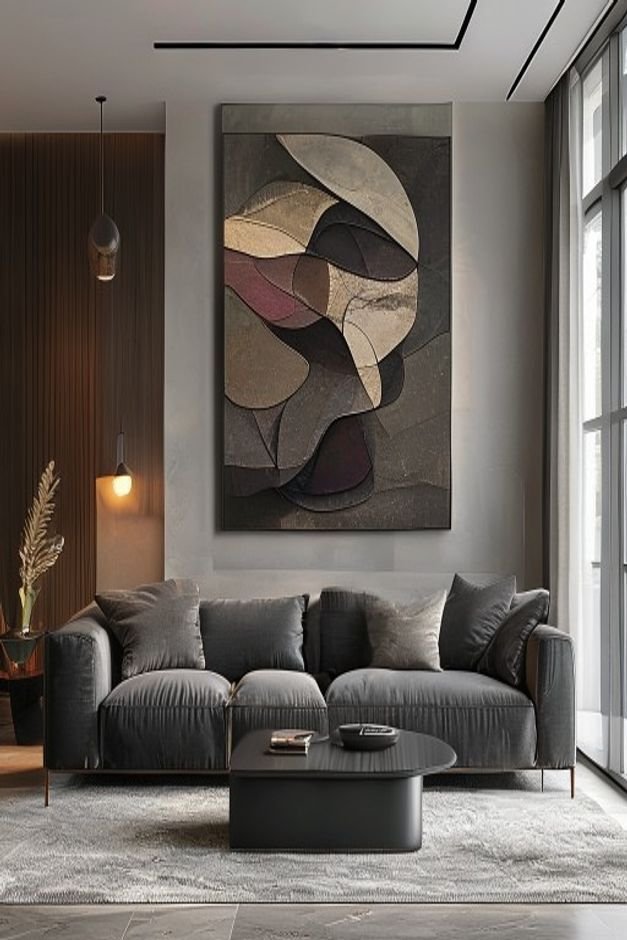 A spacious modern living room with a deep charcoal gray sofa Above it a single oversized abstract art piece in muted ton