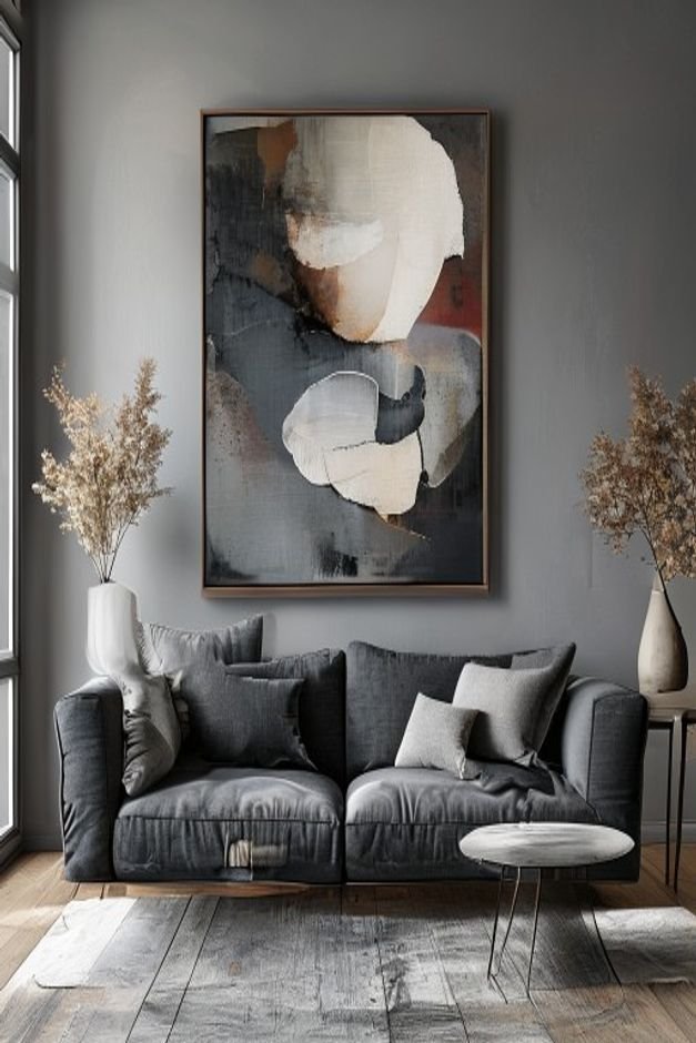 A spacious modern living room with a deep charcoal gray sofa Above it a single oversized abstract art piece in muted ton