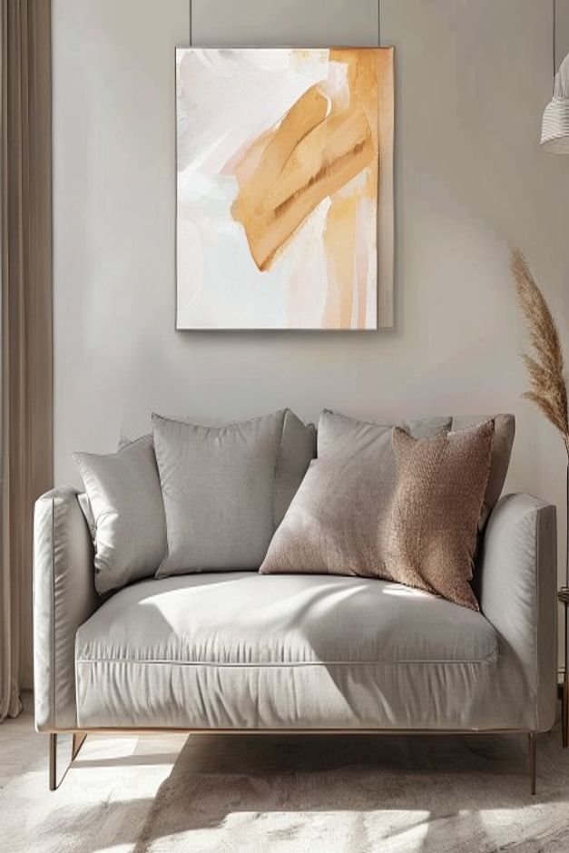 A close-up eye-level shot of a large modern sofa with a single perfectly scaled piece of abstract art hanging above it T