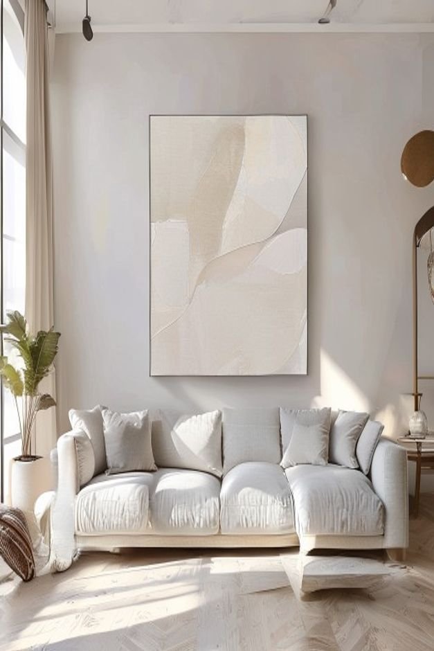 A bright airy living room with a large light grey sectional sofa Above it a single oversized piece of abstract art in ca