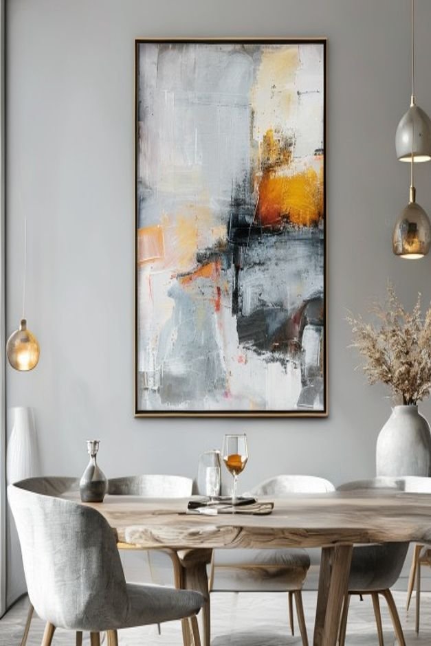 A close-up shot of a large framed abstract painting hanging on a light gray wall in a modern dining room The painting fe